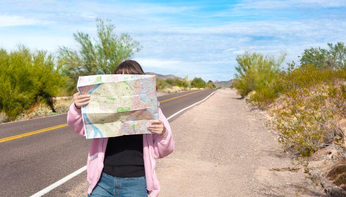 Woman holding roadmap on a desert road